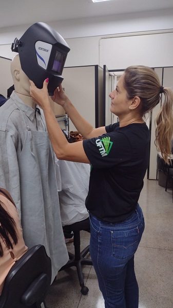 Aluna realizando a demonstração do uso dos Equipamentos de Proteção Individual recomendada para o trabalho com solda.